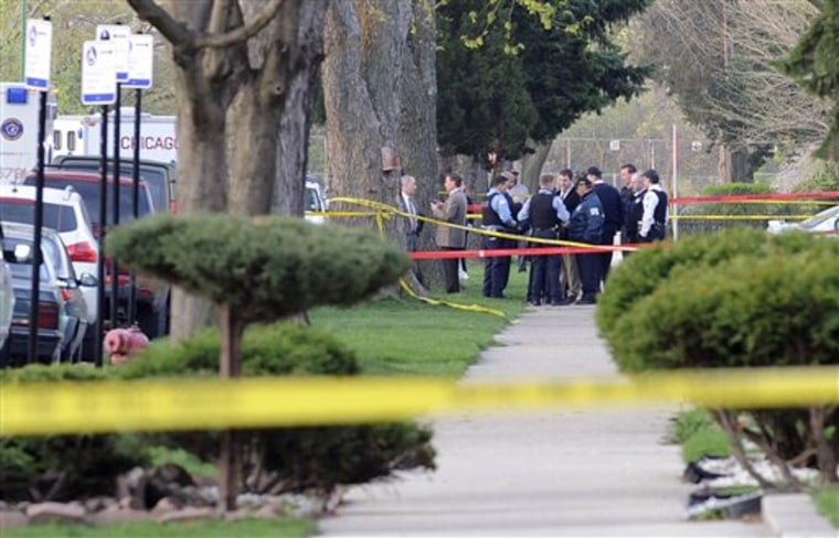 Chicago Police and investigators huddle outside a home where three children and a woman were shot dead overnight.